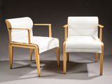 two white chairs sitting next to each other on a gray surface
