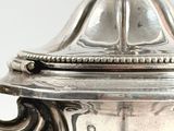 a silver plate with a lid on a white table