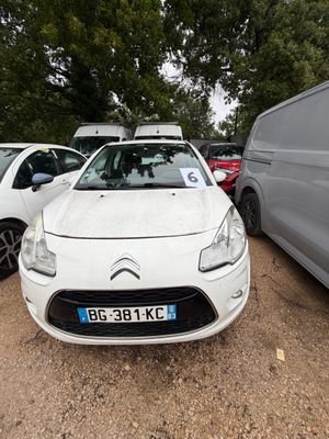 une Citrole blanche garée sur un parking à côté d'une camionnette
