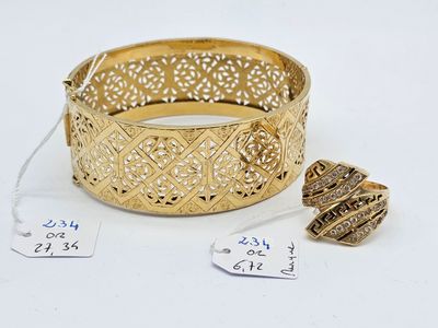 two gold bracelets and a ball of thread are on a white surface