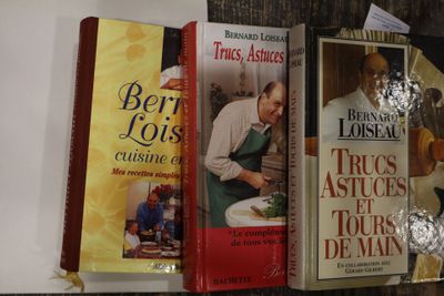 Plusieurs livres de cuisine sont alignés sur une étagère dans une cuisine