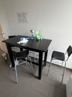 une table noire et deux chaises dans une petite pièce