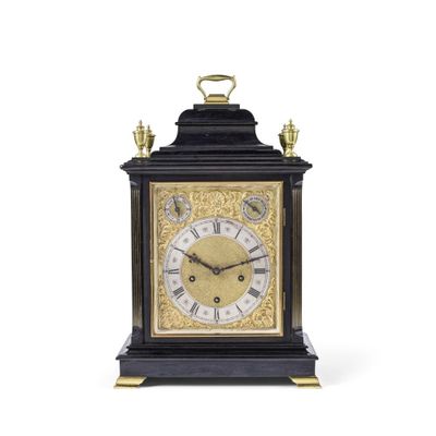 une horloge noire et or posée sur une surface blanche