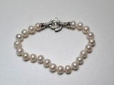 un gros plan sur un bracelet de perles blanches muni d'un fermoir en argent