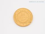 an old gold coin sitting on top of a white surface