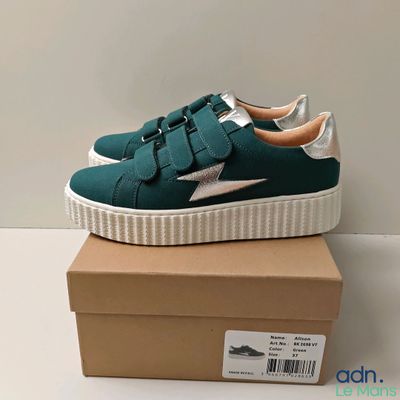 un gros plan sur une paire de baskets vertes posées sur une boîte