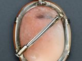 silver and pink stone pendant with a gold bar on a black surface