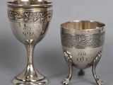 pair of silver goblets and a cup on a stand