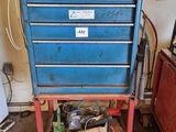 une boîte à outils bleue posée sur un chariot rouge dans un garage