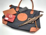 un sac noir muni d'une poignée marron et sur lequel sont posés quelques autres objets