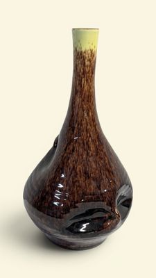un vase marron avec un couvercle vert posé sur une surface blanche