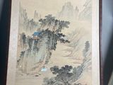 two framed asian paintings of mountains and trees on a table