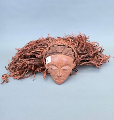 une image représentant un masque en bois aux longs cheveux sur fond bleu