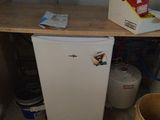 a small white refrigerator in the corner of a room
