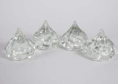 four clear glass pieces of candy sitting on top of a white surface