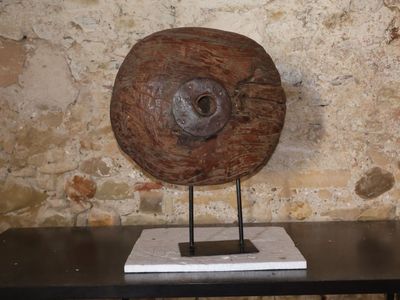 une sculpture en bois posée sur une table devant un mur de pierre