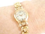 a woman ' s wrist that has a gold watch on it