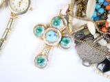 a lot of jewelry on a white table with a clock