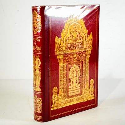 a red book with gold designs on it on a white surface