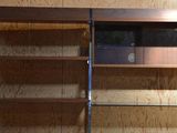 a wooden bookcase with a glass door in the corner