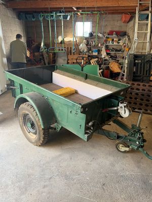 an image of a man working in a workshop with a green trailer