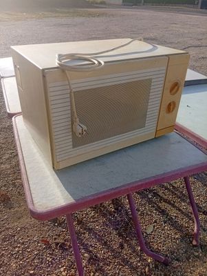 a microwave sitting on top of a table in a parking lot