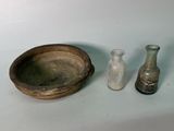 trois petites bouteilles en verre et un bol en bois posés sur une table