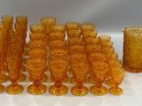 a lot of orange glass cups and pitchers on the table