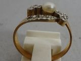 a gold ring with a pearl in it on a marble block