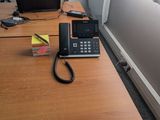 a desk with a phone, a laptop and a bag on it