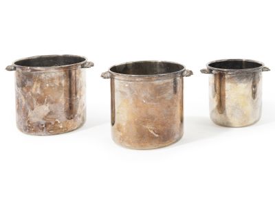 three metal pots sitting next to each other on top of a white surface