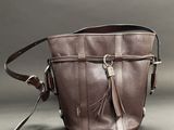 brown leather purse with tassels on a grey background