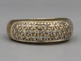 un gros plan d'une bague en or et diamants posée sur une surface grise