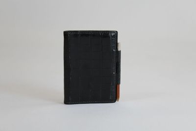 un portefeuille noir surmonté d'un porte-cartes, posé sur une surface blanche
