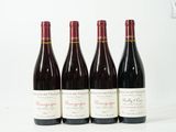 quatre bouteilles de vin sont alignées sur une surface blanche