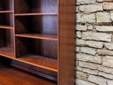 an image of a wooden bookcase in front of a brick wall