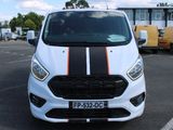 une camionnette blanche ornée d'une bande noire et orange, garée sur un parking