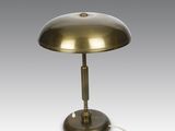 une lampe de table en laiton avec un cordon blanc sur fond gris