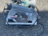 une scie circulaire posée par terre à côté d'une paire de chaussures