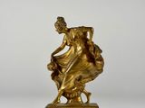 a gold statue of a woman sitting on top of a marble base