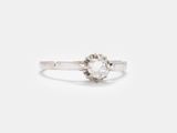 un gros plan d'une bague sertie d'un diamant blanc sur une surface blanche