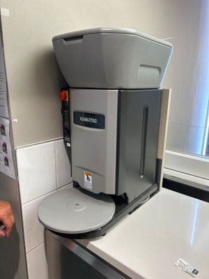 un homme debout à côté d'une cafetière dans une cuisine