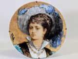 une assiette sur laquelle est représentée une femme portant un chapeau bleu