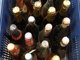 a blue basket full of bottles of beer on the floor