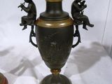 a bronze vase with three children sitting on the top of it