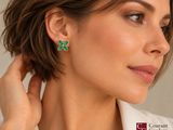 a woman wearing a white shirt and green clover earrings