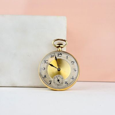 une montre de poche en or posée sur un bloc de marbre