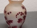 a white vase with red flowers on it sitting on a table