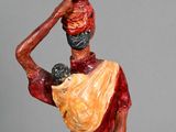 statue of a man carrying a basket on his head with a baby in his arms