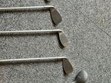 several golf clubs are lined up on a rack on the floor